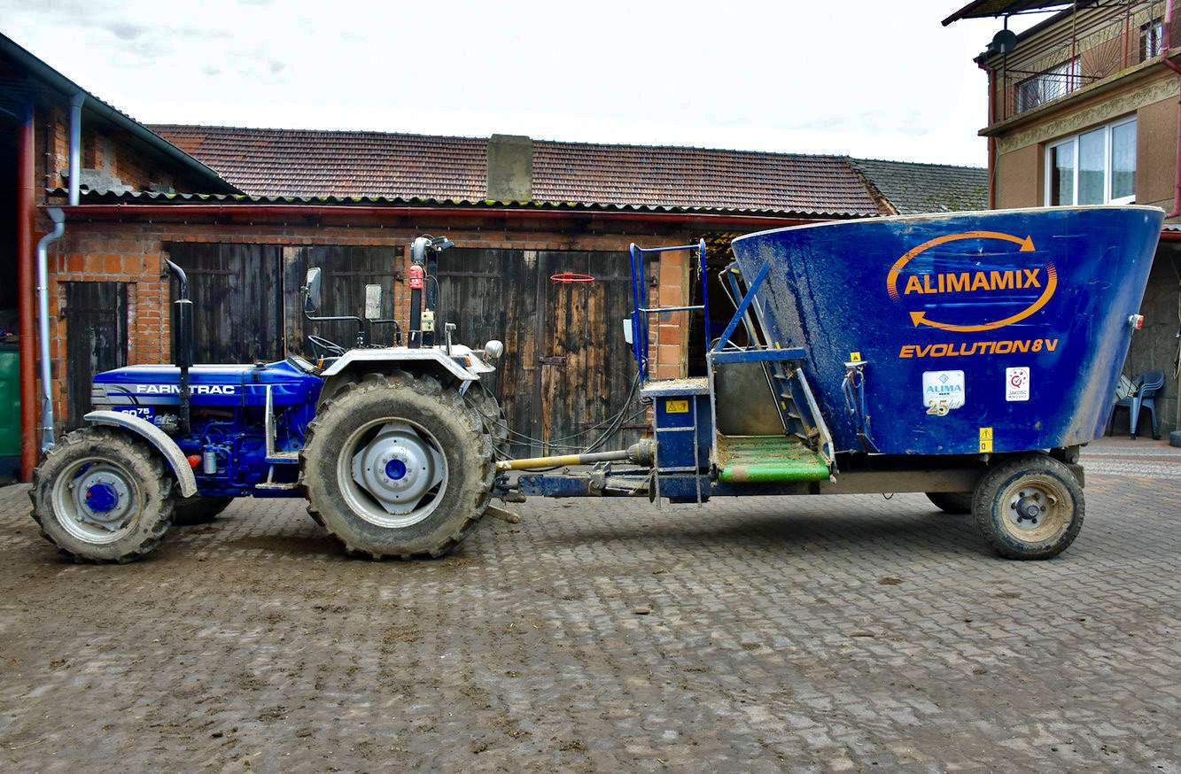 Wóz paszowy polskiego producenta A-Lima-Bis ze Środy Wielkopolskiej współpracuje z prostym mechanicznym ciągnikiem Farmtrack, który nie posiada kabiny, tak aby mógł wjechać do stropowej obory